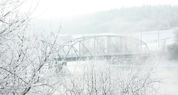 Old Trestle Bridge spaning River. Early morning mist and snow.