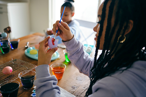 Young girls sitting at a home table, dyeing and decorating Easter eggs.
