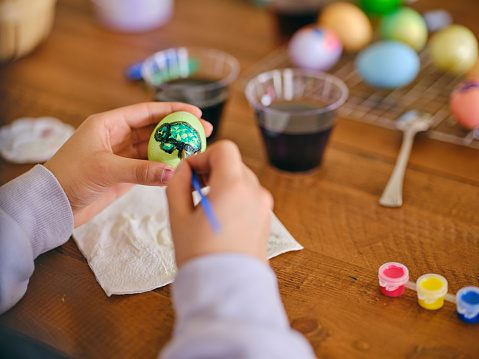 Young girls sitting at a home table, dyeing and decorating Easter eggs.