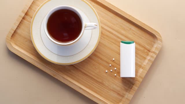 artificial sweetener container and cup of tea on table