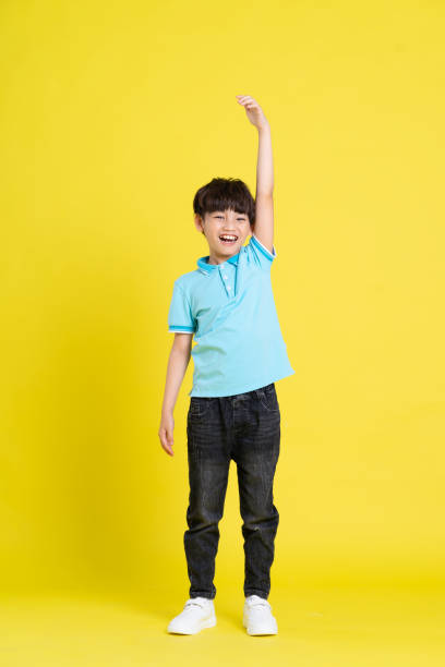 istock full body image of asian boy posing on yellow background 1471103375