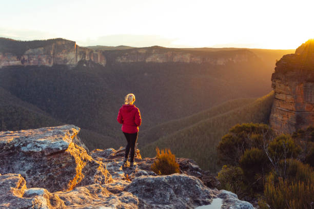 istock Sunlight streaming into valley and onto a cliff ledge hiker standing 1471106546