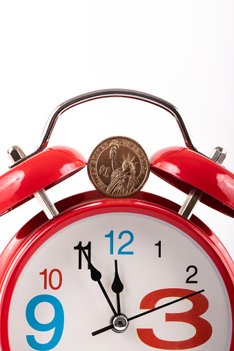 1 american dollar coin and red alarm clock on white background