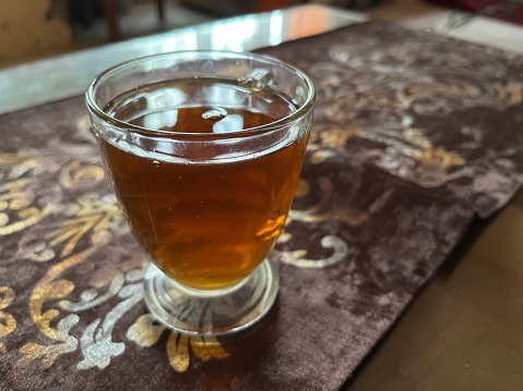 A glass cup of freshly brewed black tea on the table in a house.