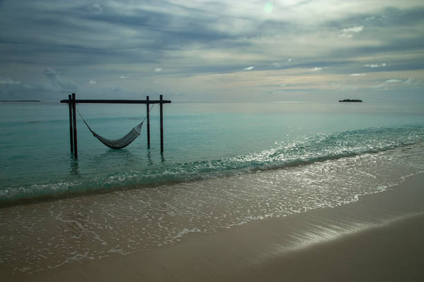 Mature woman relaxes in hammock on edge of sea, Mui Ne
