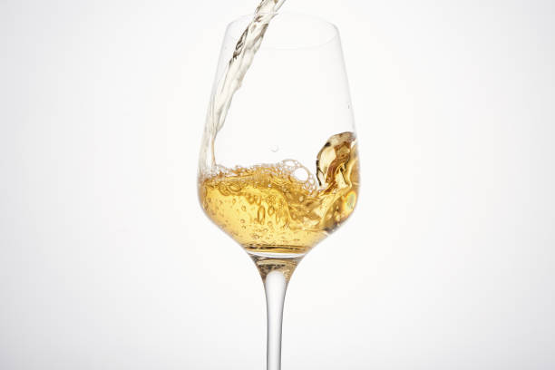 istock Stream of white wine flows into stem glass, swirls. 1471118802