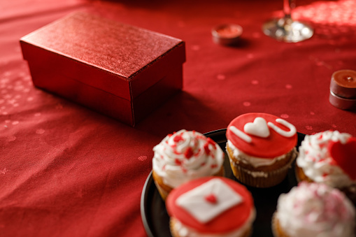 A table set with a red tablecloth, adorned with a gift, and muffins, ready for a Valentine's Day celebration