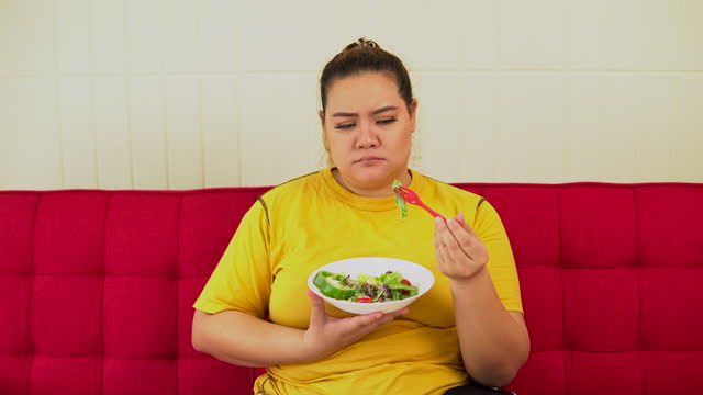 Overweight  woman boring to eating salad