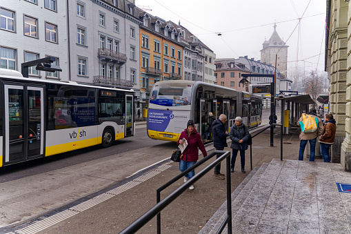 Yellow white buses at bus station railway station at Swiss City of Schaffhausen on a foggy winter day. Photo taken February 16th, 2023, Schaffhausen, Switzerland.