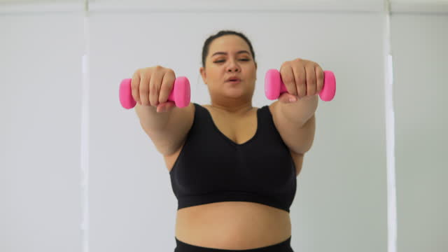 Overweight woman talking dumbbell at home