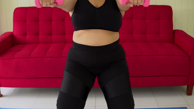 Overweight woman talking dumbbell at home