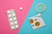 Contraceptive pills and condoms on colored background. Concept of birth control