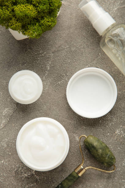 istock Face massage roller with cosmetic cream on grey background. Vertical photo 1471130342