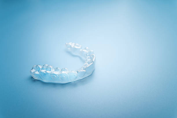 Close up invisible aligners on the blue background with copy space. Plastic braces dentistry retainers to straighten teeth stock photo