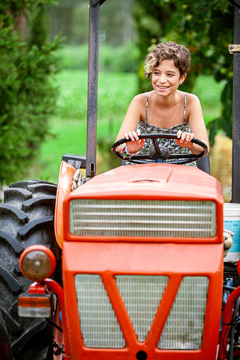 Cute girl near the modern tractor in the field. The concept of field work, agricultural machinery.