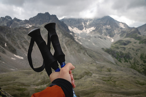 Close-up of female hands with trekking poles for Nordic walking against the background of the Alpine mountains, distant Caucasian rocks.