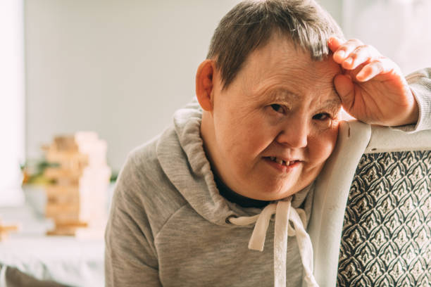 Portrait of an elderly smiling woman with Down syndrome in a sunny room stock photo