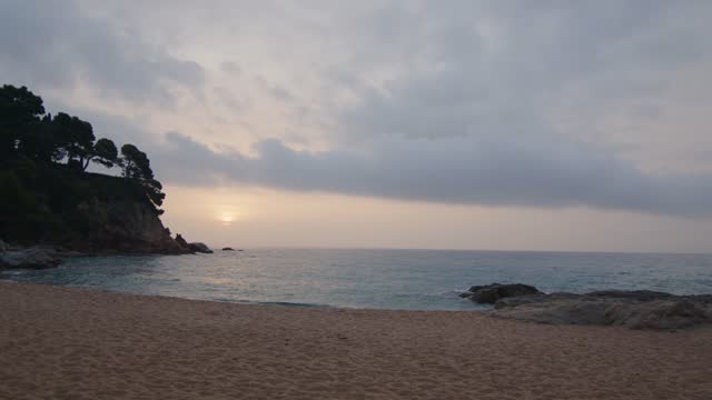 Still shot of a wild beach by the sea at a cloudy sunrise, in Spain