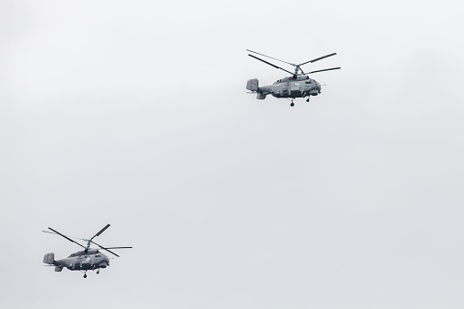 Two Kamov Ka-27 military Russian helicopters fly in cloudy sky on a daytime