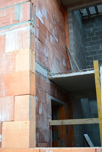 Construction worker with a jackhammer and saw has shortened concrete precast floor stair landing 10 cm, 3.9 inches because the architect had drawn a plan without providing reserve maneuvering space in stairwell precast concrete stairs