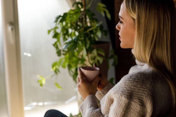 istock A young woman is enjoying a warm cup of coffee while deep in thought in her comfortable living room 1471150570
