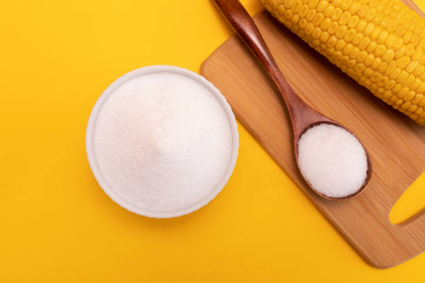 edulcorante naturale erythritol, prodotto dalla fermentazione dal mais in ciotola di ceramica, cucchiaio di legno, pannocchia di mais su sfondo giallo arancio. dolcificante. piano orizzontale, vista dall'alto - zero carb foto e immagini stock