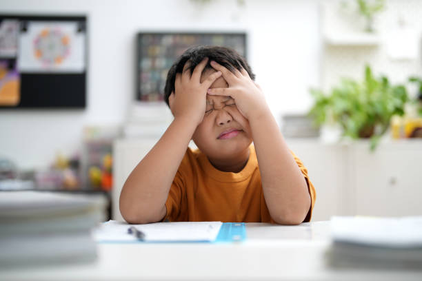 Worried young school boy studying at home Young Asian boy is tired of doing homework, sitting at the table. asian child avoiding stock pictures, royalty-free photos & images