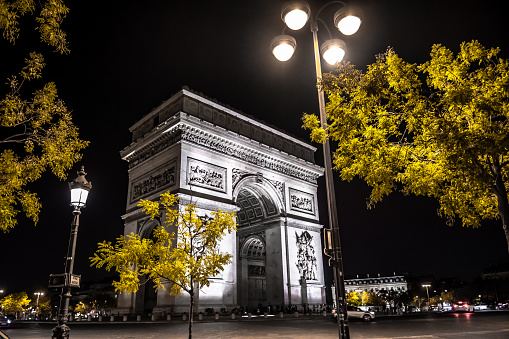 Illuminated Arch De Triomphe De L'Étoile On Place Charles De Gaulle And Champs Elysees In The Night In Paris, France