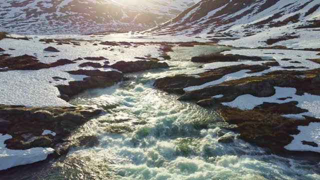 Low flight over a wild river cascade on a high and snowy mountain plateau wilderness in Norway