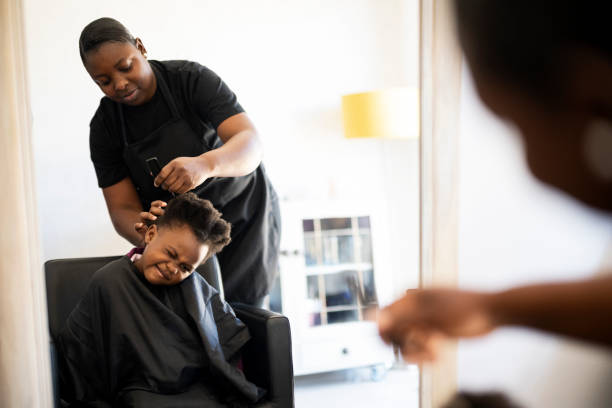 istock Little girl pulls a face while hairdresser combs her hair 1471171696