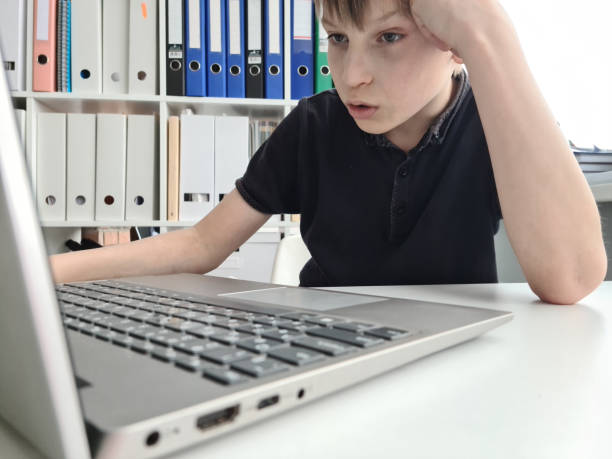 istock Boy boy makes homework computer. Sad child is tired of tired is sad child 1471172003