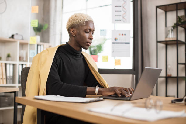istock Successful african businessman in stylish suit working on laptop computer on modern office. 1471173324