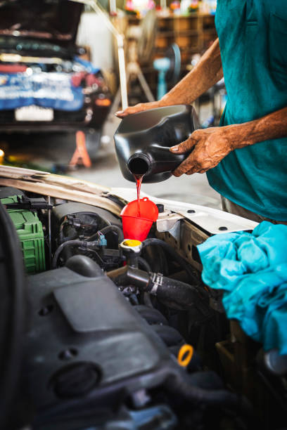 mechanic pouring oil to car engine. - old men car oil imagens e fotografias de stock