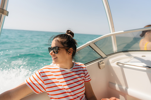 Photo of a smiling woman enjoying a summer day on the motor boat