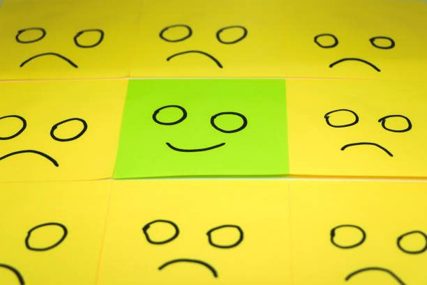 concept for a positive attitude with small office notes with multiple faces and one that stands out with a smile