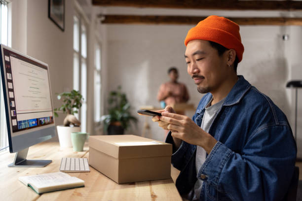 istock Young Asian man scanning QR code on the package at home 1471182029