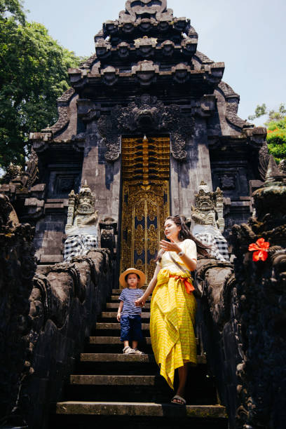 mujer asiática y su hijo visitando un templo de pura, hinduismo bali - bali indonesia temple travel fotografías e imágenes de stock