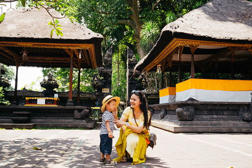 Asian woman and her son visiting a Pura, Hinduism Bali temple