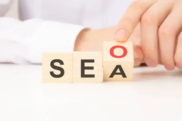 Photo of Hand flip SEO to SEA text wooden cube blocks on table background. search engine optimization, advertising, idea, strategy, marketing concept