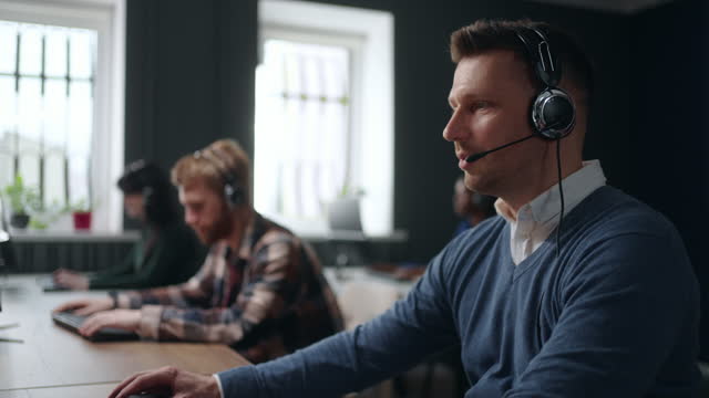 serious man answering customer call in tech support service, portrait in office of call-center