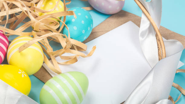 istock easter holiday card with basket, decorated easter eggs spilled from a basket onto a blue background 1471188796