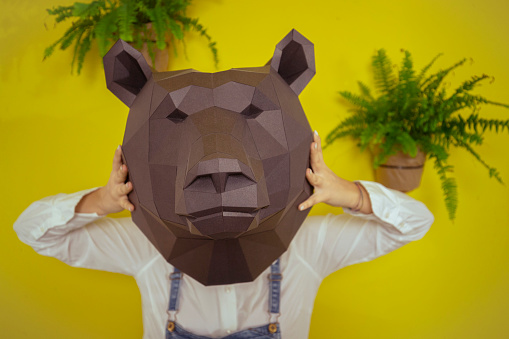 Front view of a woman holding an origami bear head over her head