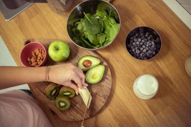Athletic woman cuts banana and other fruits to make a refreshing protein drink