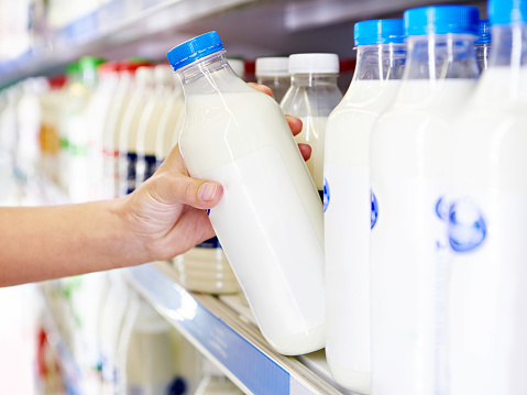 Woman chooses milk and dairy products at the grocery store