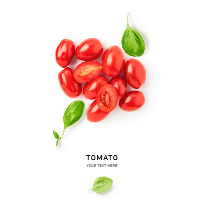 Tomato and basil leaves creative composition isolated on white background. Food, healthy eating and dieting concept. Summer red small oval tomatoes arrangement and layout