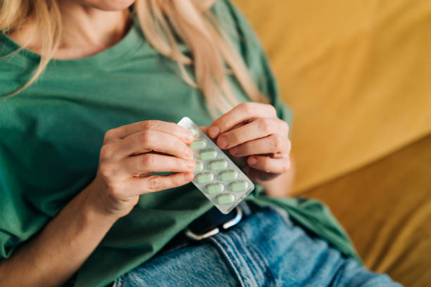 nierozpoznawalna kobieta bierze jedną tabletkę z paczki tabletek. - diet pill zdjęcia i obrazy z banku zdjęć