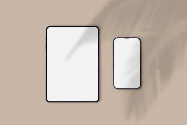 istock Tablet and mobile phone with white screen for editing on a brown background and palm tree shadow. 1471217625
