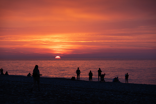 Silhouette of people on a beach enjoying the sunset.