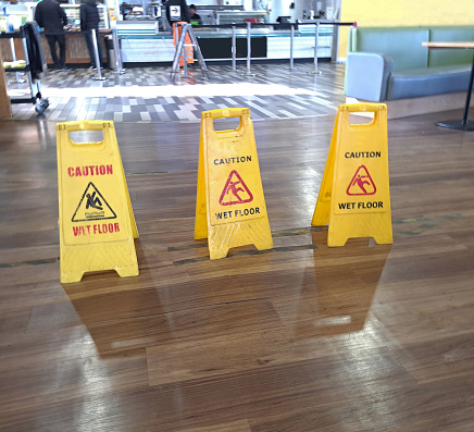 Warning signs in place on laminate floor in service station, warning people to take care on the wet floor.