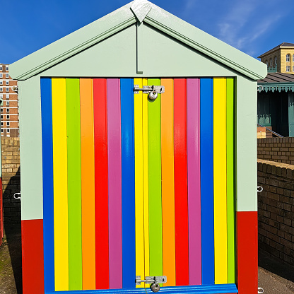 Brightly coloured freshly painted stripy  beach hut in Brighton England, a town well known for its Gay community